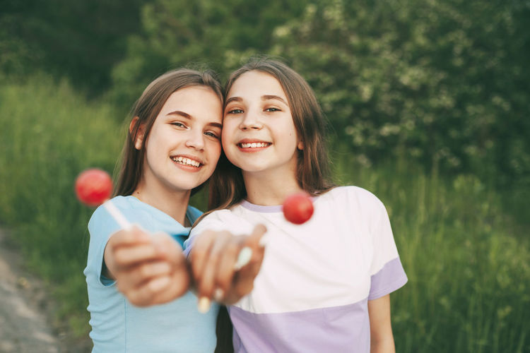 Portrait of smiling sisters holding lollipops