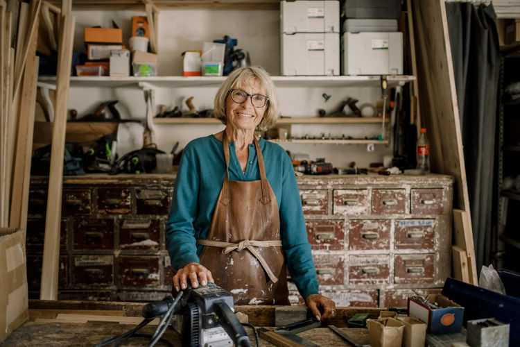 Portrait of smiling senior female entrepreneur standing at workshop