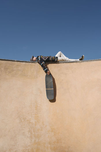 Woman holding skateboard lying on sports ramp