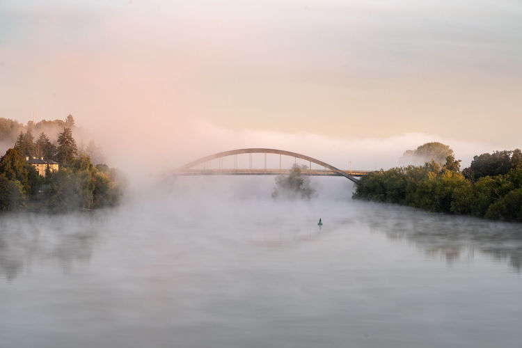 Arch bridge over lake against sky during sunset