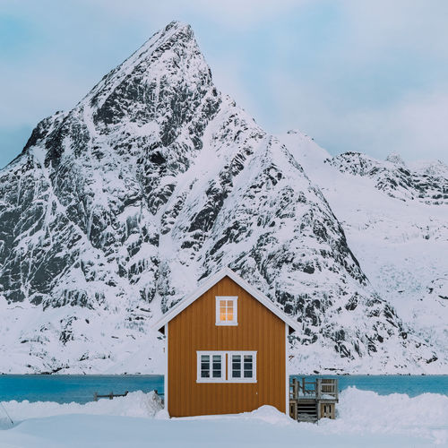 Snow covered house and mountain against sky