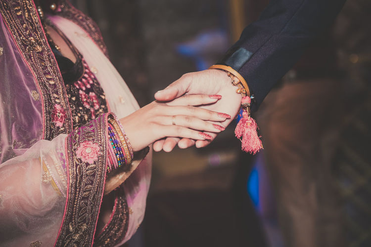 Midsection of bride holding groom hands
