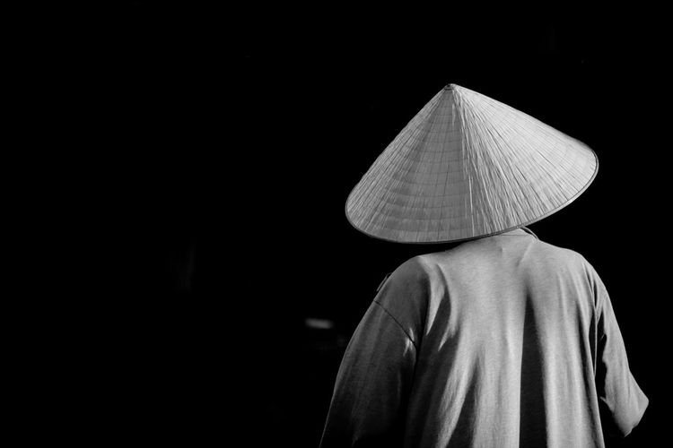 Rear view of man wearing hat standing at night