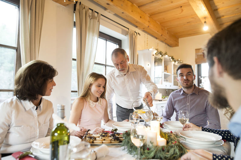 Senior man pouring water into glass at christmas dinner table