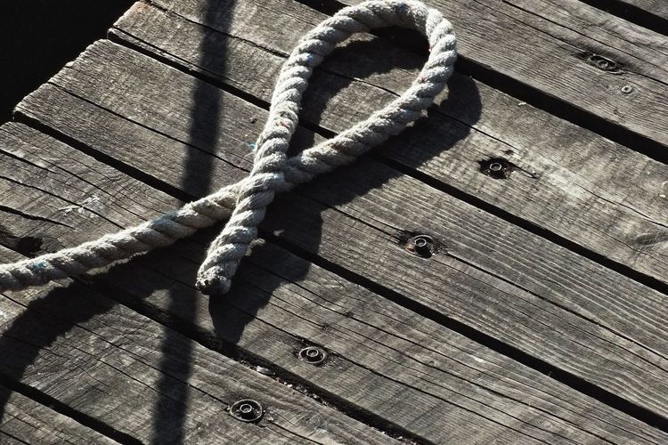 High angle view of rope tied to wooden pier