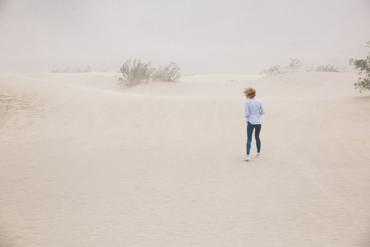 Rear view of woman walking on sand dune at death valley