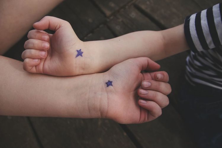 Cropped image of friends showing hands with star shapes