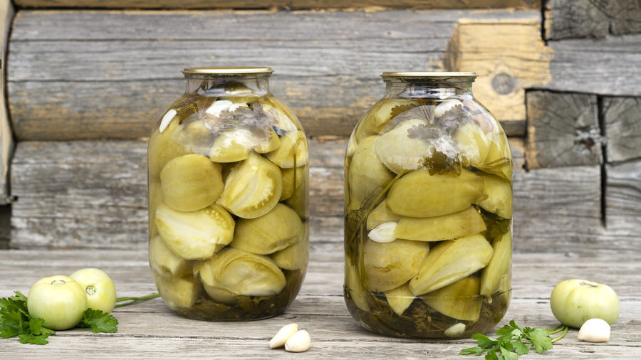 Homemade pickled green tomatoes in a glass jars with garlic and parsley. home preservation.