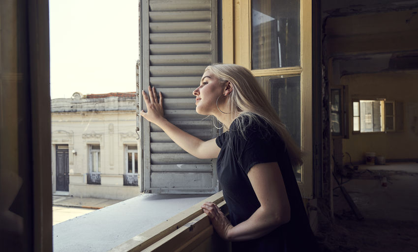Side view of woman standing against window
