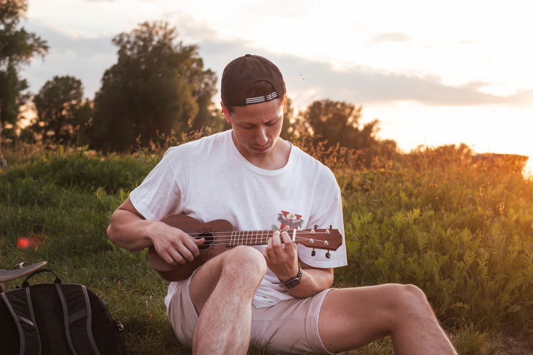 Man playing ukulele during sunset