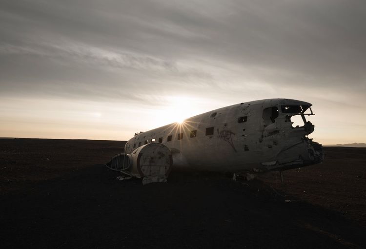 Abandoned airplane on landscape against sky during sunset