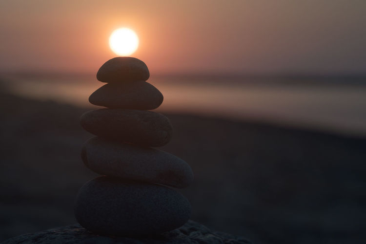 Stack of stones at beach during sunset