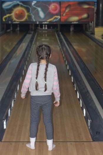 Rear view of girl standing at bowling alley