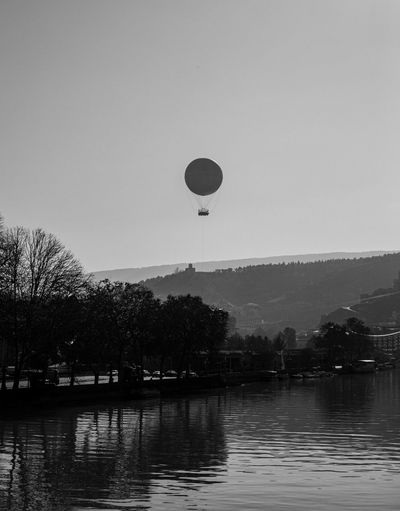 Hot air balloon flying over river against sky