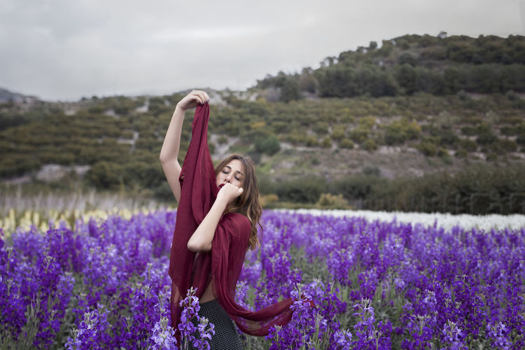 Woman standing on purple flowering plants on field