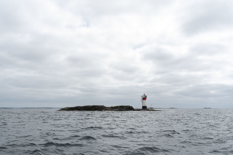 Lighthouse at sea against sky