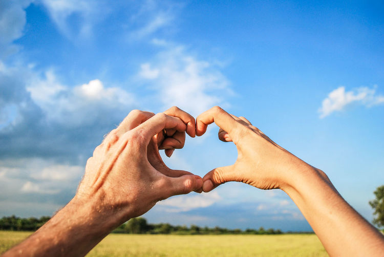 Couple hand make heart picture with blue sky and cloud. romantic scene in rice flied.