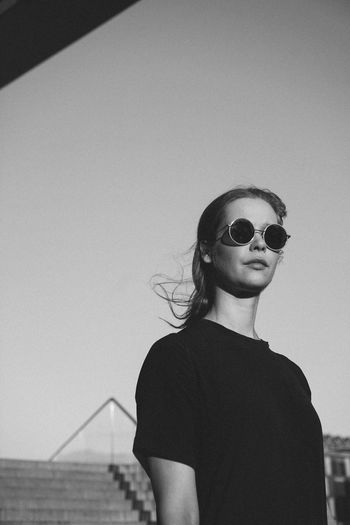 Woman wearing sunglasses standing against clear sky
