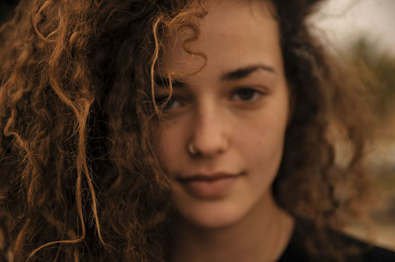 Close-up portrait of young woman with curly hair