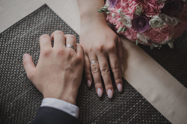 Midsection of newlywed couple holding hands on table