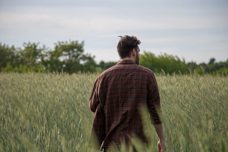 Rear view of young man walking on field