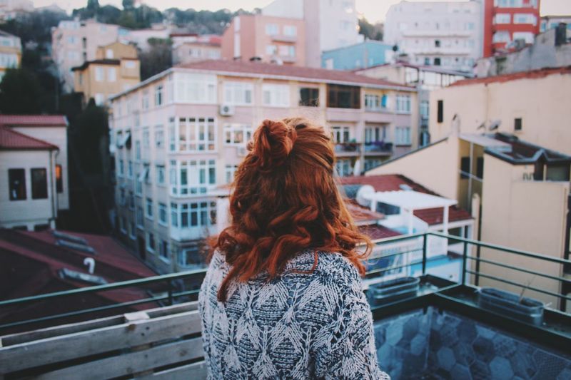 Rear view of woman looking at city from balcony