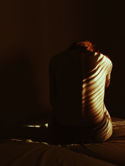 Shirtless woman sitting in darkroom at night