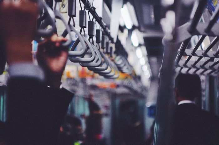 Cropped image of people holding handles in subway train 