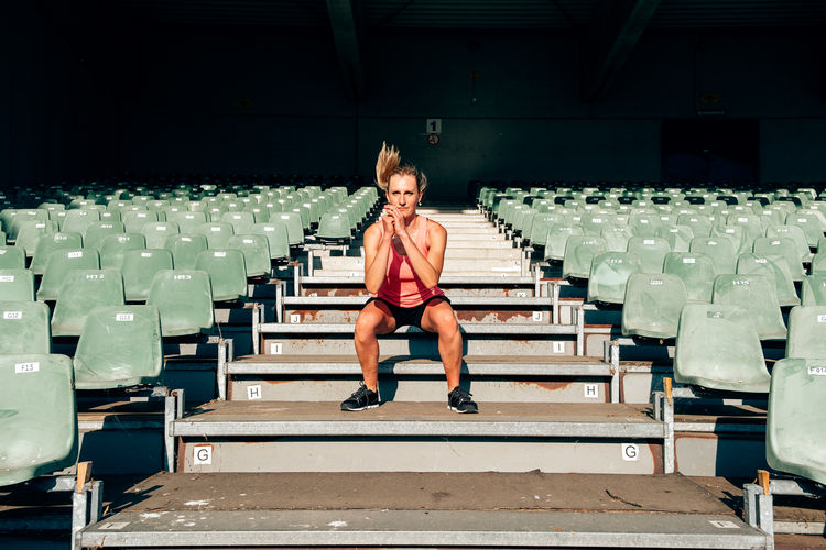 Front view of a fit and healthy woman workingout at the stadium jumping up and down the steps 