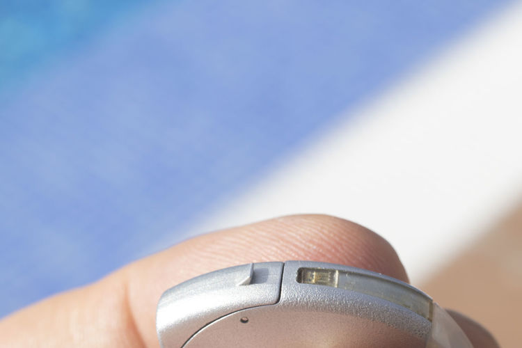 Close-up of hand holding hearing aid outdoors