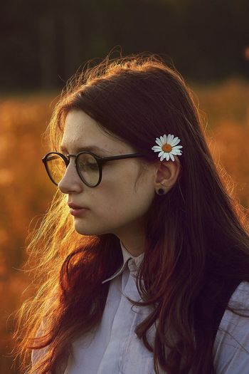 Close-up of woman wearing white daisy during sunset