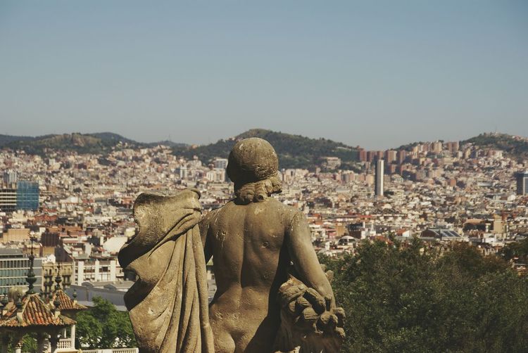 Naked statue overlooking cityscape