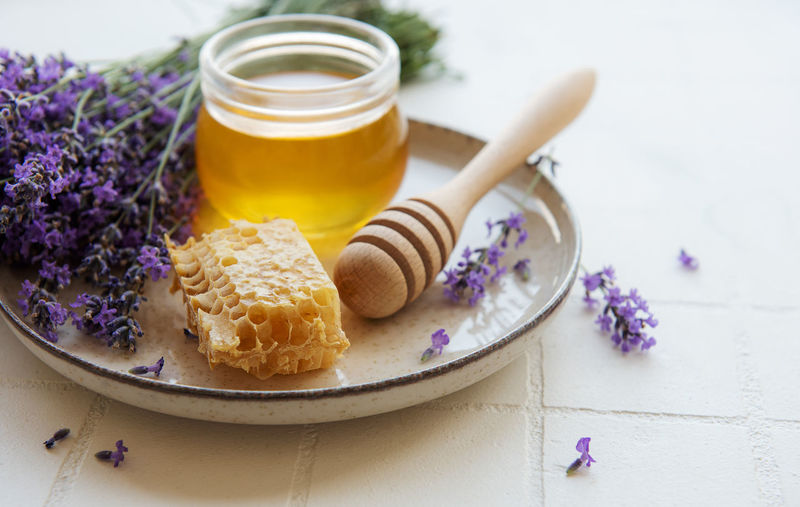 Glass of honey, honeycomb and lavender flowers