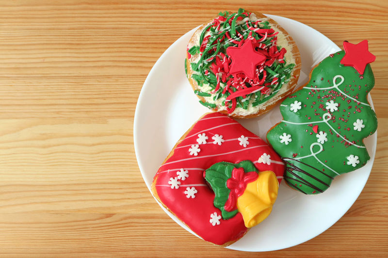 Plate of vivid color christmas decorated sweets served on wooden table with free space