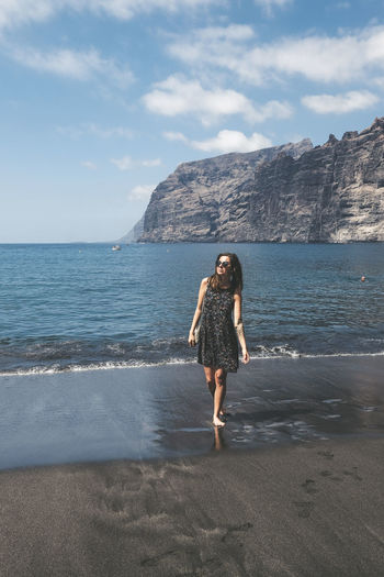 Woman standing on black sand beach against sky