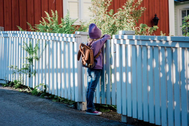 Young girl leaning on a fence looking into the distance waiting