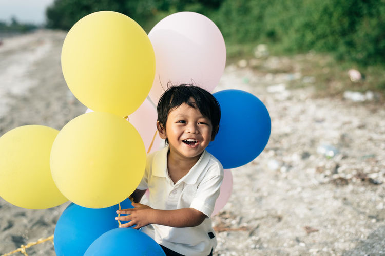 High angle view of boy holding balloon while standing on ground