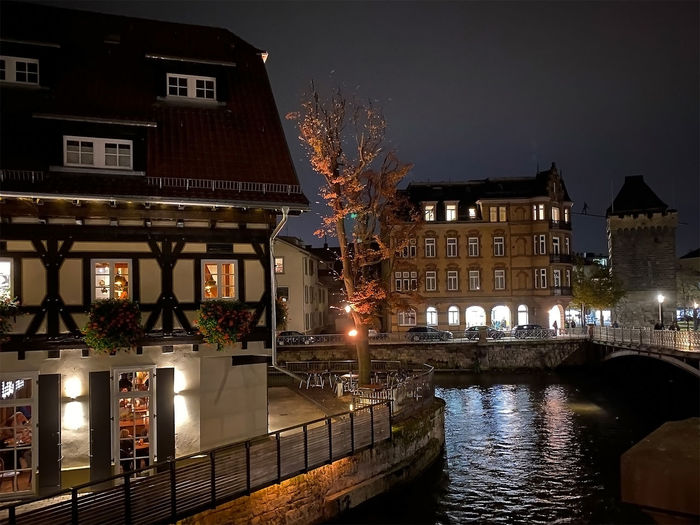Illuminated buildings by canal against sky at night