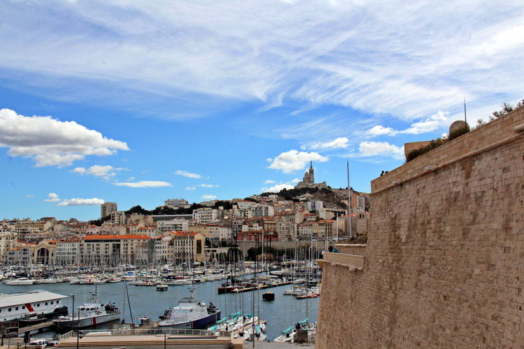 Sailboats moored in sea against buildings in city
