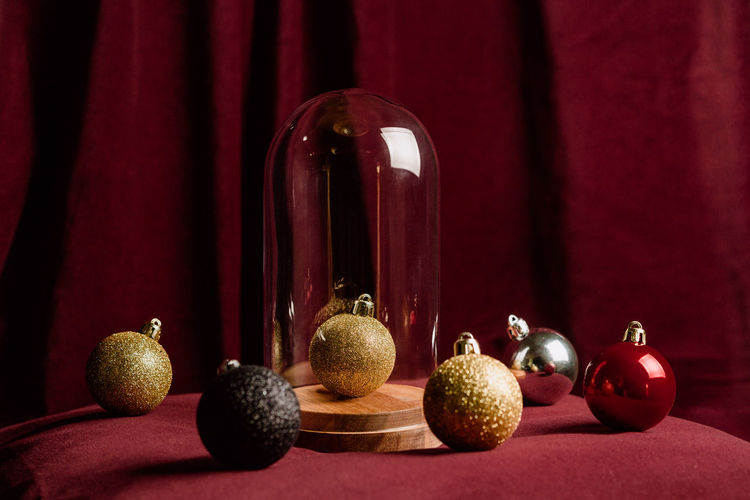 High angle of collection of sparkling christmas balls arranged on red soft bed at home