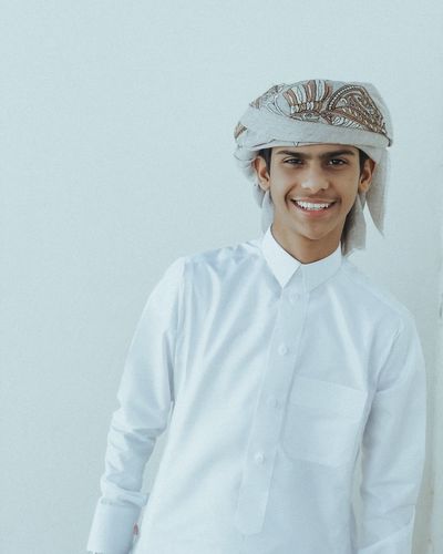 Portrait of smiling young man wearing traditional clothing against white background