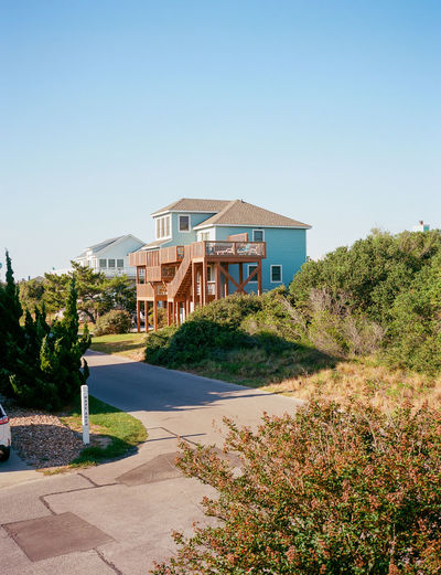 Houses by trees against clear blue sky