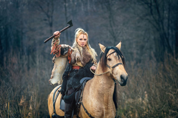 Portrait of woman with hand tool riding horse in forest