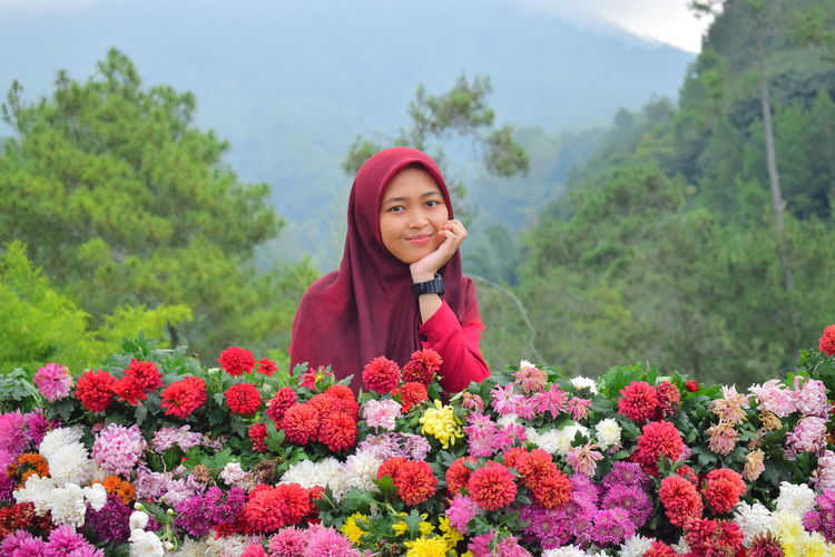 Young woman standing by flowering plants