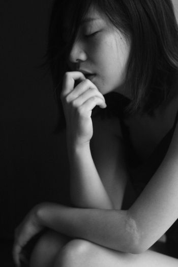 Close-up of young woman depressed woman sitting in darkroom