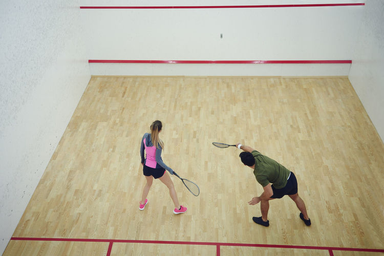 High angle view of man and woman playing tennis on floor