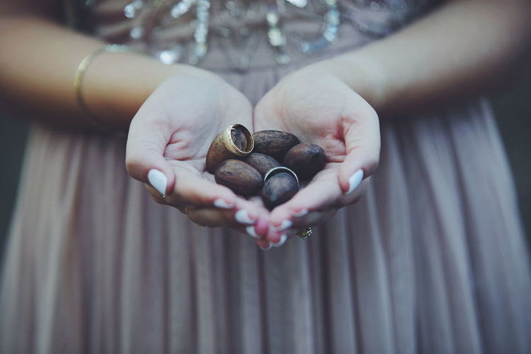 Midsection of bride holding wedding rings and seeds