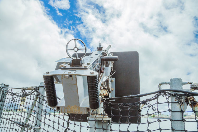Low angle view of machinery against cloudy sky