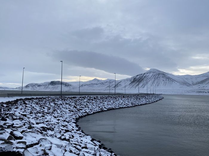 Scenic view of lake by snowcapped mountains against sky