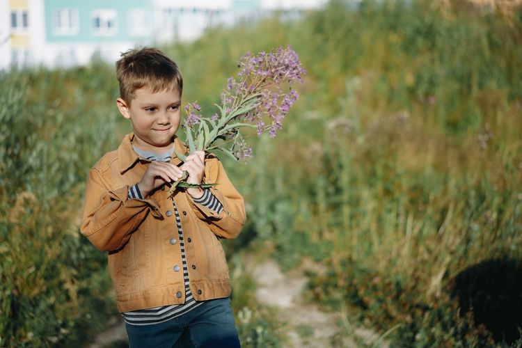 Boy holding flowers standing in field